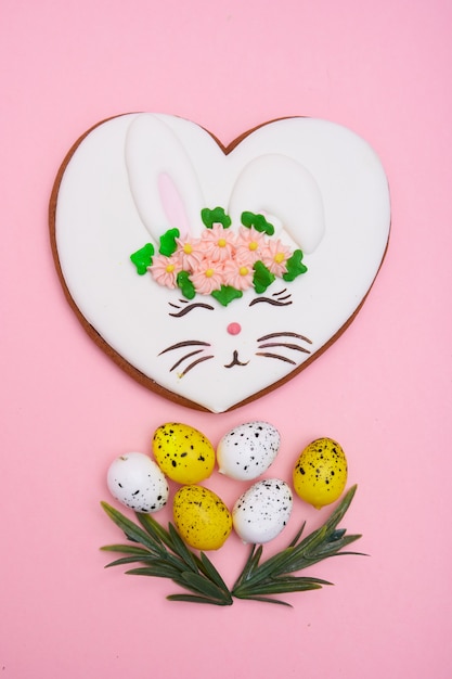 Easter bunny, gingerbread with glaze with quail eggs on pink table Copy space