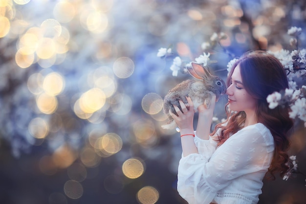 easter bunny in the hands of a beautiful girl, spring, april in a blooming garden, portrait of a woman