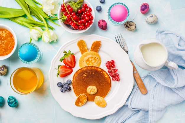 Easter bunny of pancakes with berries. Easter Breakfast table. Blue background, top view.