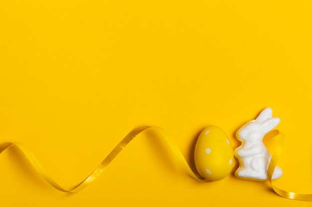 Easter bunny rabbit and eggs on a bright yellow background