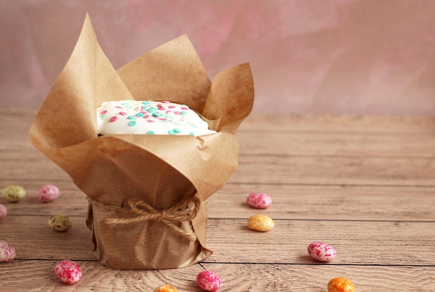 Easter cake in brown shape in white glaze sprinkled on a wooden background