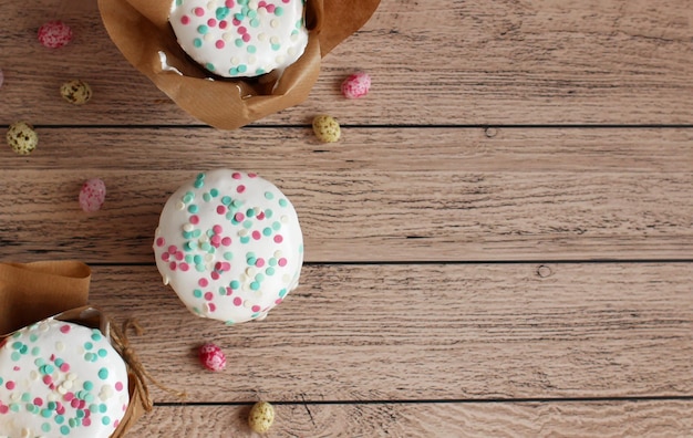 Easter cake in brown shape in white glaze sprinkled on a wooden background