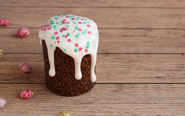 Easter cake in brown shape in white glaze sprinkled on a wooden background