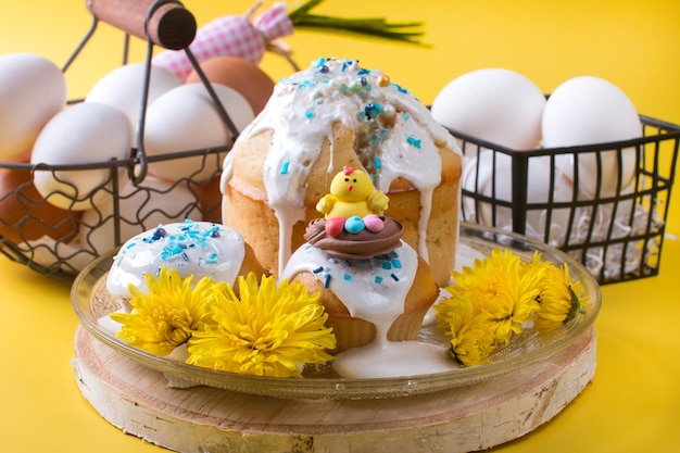 Easter cake and eggs with flowers on a yellow background The concept of the Easter party