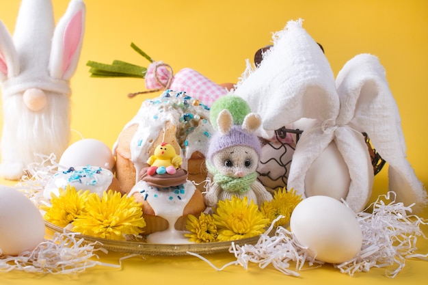 Easter cake and eggs with flowers on a yellow background The concept of the Easter party