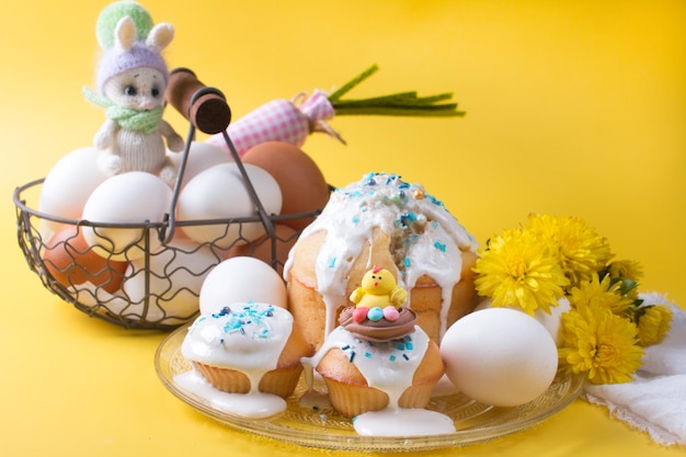 Easter cake and eggs with flowers on a yellow background The concept of the Easter party