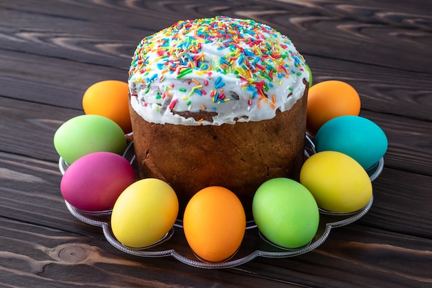 Easter cake and painted colorful eggs on dark wooden boards.