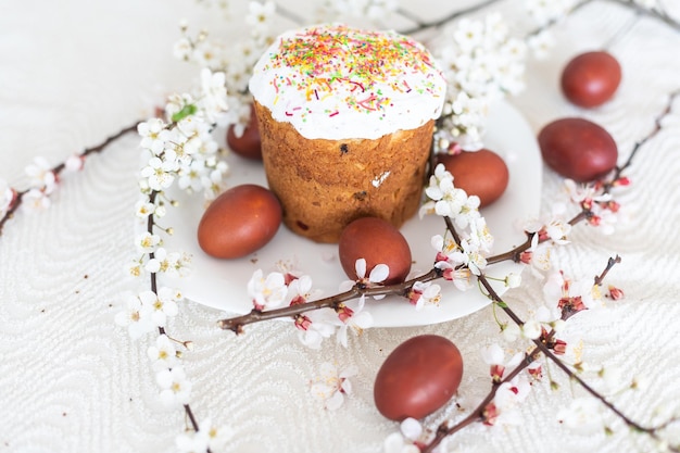 Easter cake and painted eggs. Blooming bouquet laying on the table near.