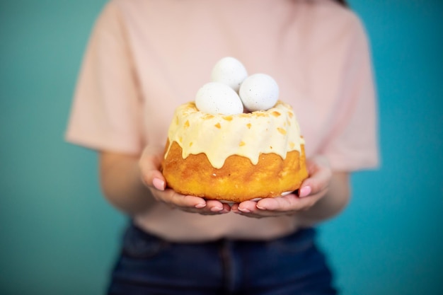 Easter cake with eggs in hands on blue background Polish babka traditional Easter funnel cake