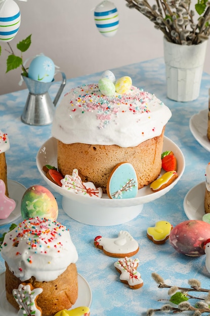 Easter cakes and eggs on a festive Easter table with willow and a figurine of a rabbit on a blue background