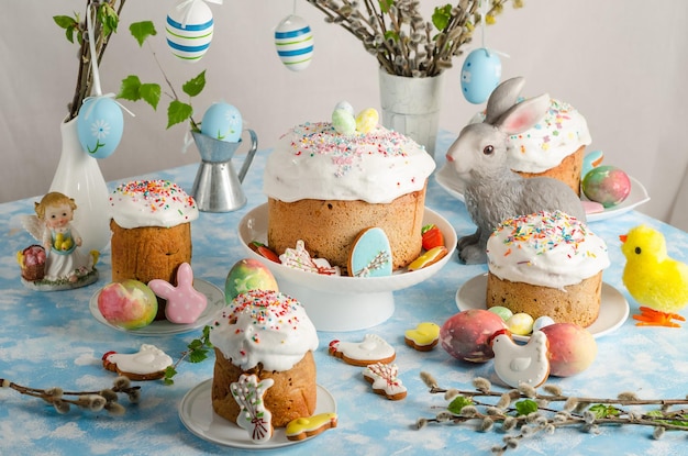 Easter cakes and eggs on a festive Easter table with willow and a figurine of a rabbit on a blue background