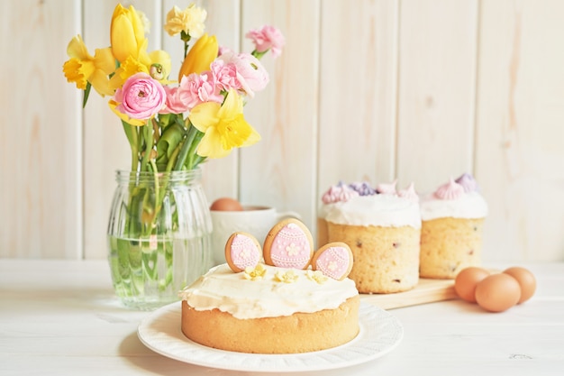 Easter cakes on table, macaroons, eggs and bouquet of flowers in vaseaster 