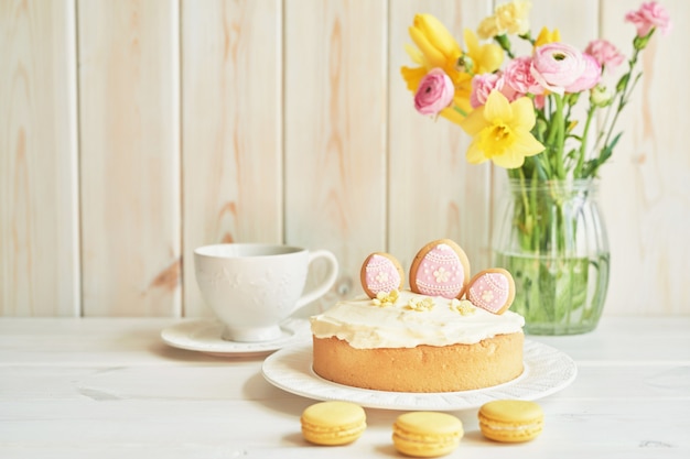 Easter cakes on table, macaroons, eggs and bouquet of flowers in vaseaster 