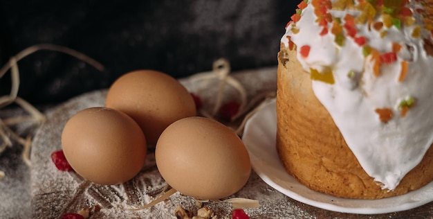 Easter cakes on the table in a plate next to the chicken eggs on a wooden board black background