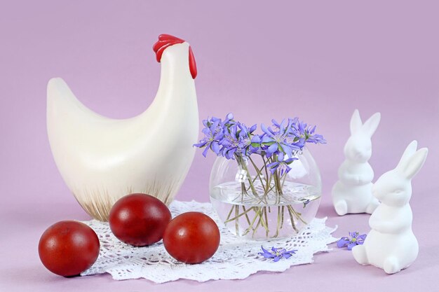 Easter card figurines of chicken and rabbits painted eggs a bouquet of spring flowers on a pastel background space for text