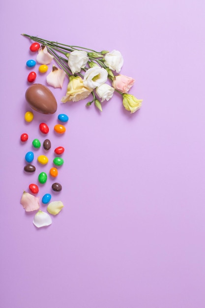 Easter chocolate eggs and flowers on purple  paper background