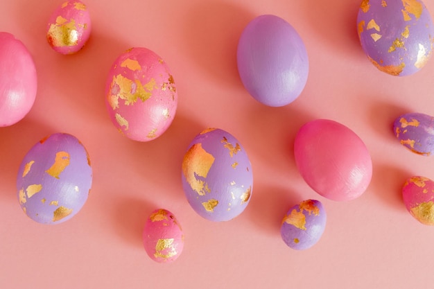 Easter colored eggs with golden foil on the pink pastel background