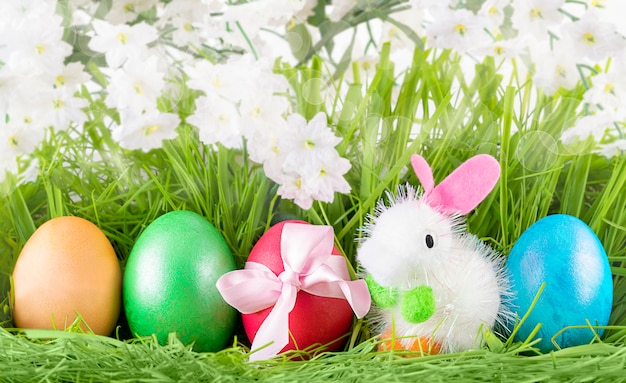 Easter Colorful Decorated Eggs and Little Toy Bunny on Green Grass