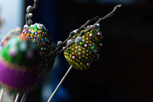 Easter colorful eggs decorated with bright color threads and beads with willow osier tree branch