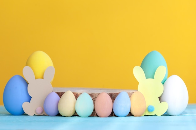 Easter colorful eggs with wooden empty platform on yellow background