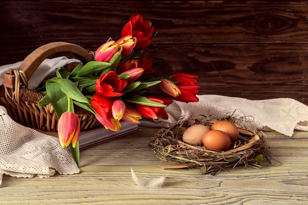 The easter composition Eggs and red tulips on wooden background closeup