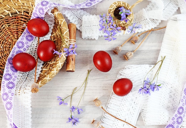 Easter composition painted eggs among lace and ribbons blue flowers and poppy branches top view