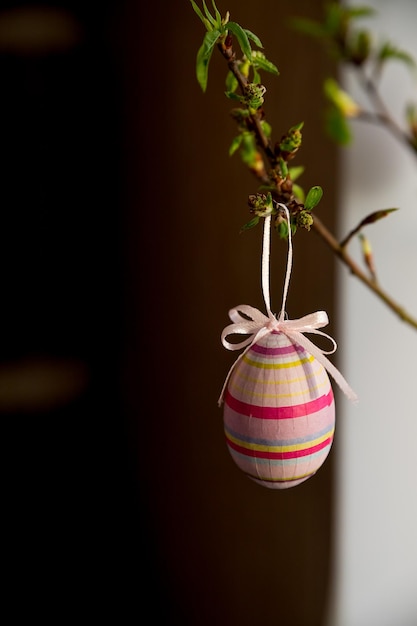 Easter composition tree branches with green small leaves and colorful Easter eggs on blurred backgroundConcept interior design for spring holidays