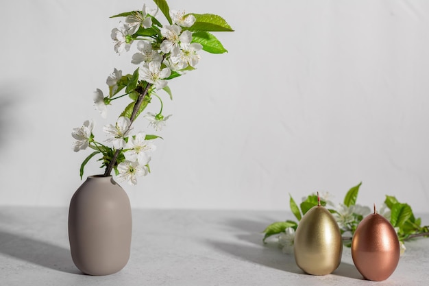 Easter composition with blooming branches and eggs shaped candles