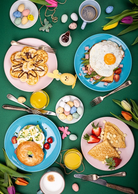 Easter composition with breakfast flat lay with scrambled eggs bagels, tulips, pancakes, bread toast with fried egg and green asparagus, colored quail eggs. Top view