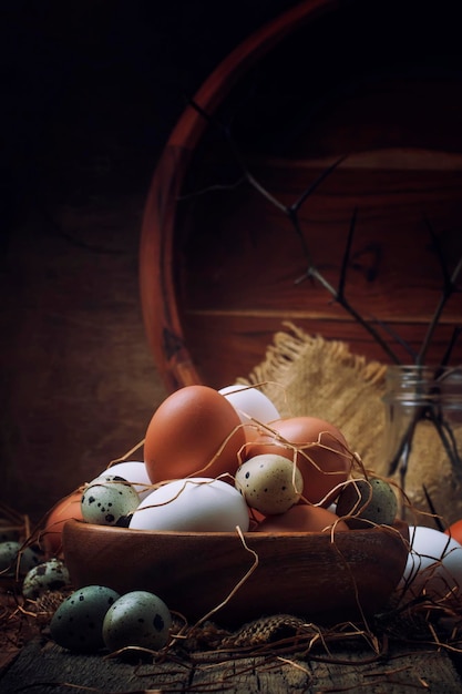 Easter composition with colorful chicken and quail eggs in rustic style vintage wooden background selective focus