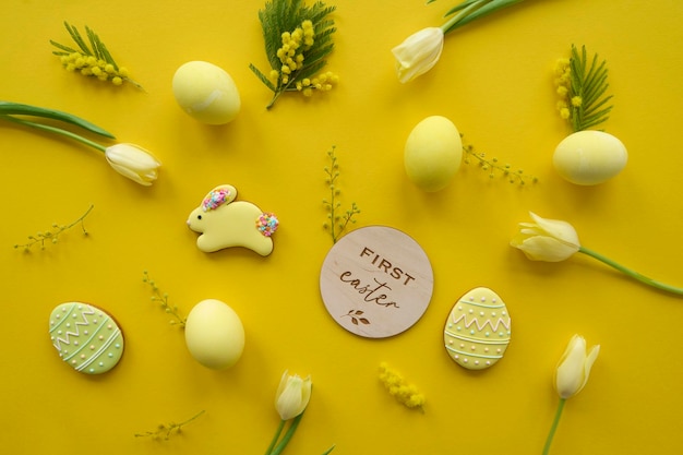 Easter composition of yellow tulips eggs and cookies on a yellow background