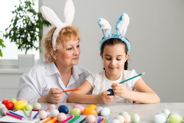 Easter concept. Grandmother with granddaughter are holding Easter eggs at home.