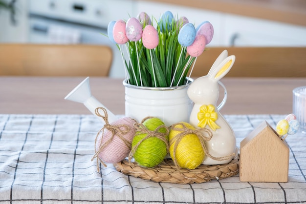 Easter decoration of colorful eggs in a basket and a rabbit on the kitchen table in a rustic style Festive interior of a country house