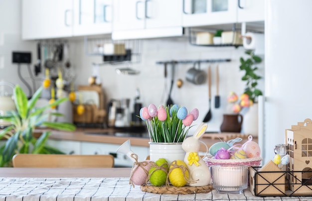 Easter decoration of colorful eggs in a basket and a rabbit on the kitchen table in a rustic style Festive interior of a country house