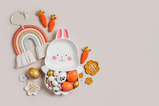 Easter decoration with cute plate in the shape of a bunny with Easter eggs candy carrot and flowers Happy Easter concept Idea for Easter dinner