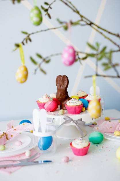 Easter decorations - decorated table with cupcakes, colorful painted easter eggs and chocolate bunny