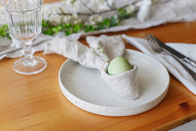 Easter egg in bunny napkin on plate stylish Easter brunch table setting