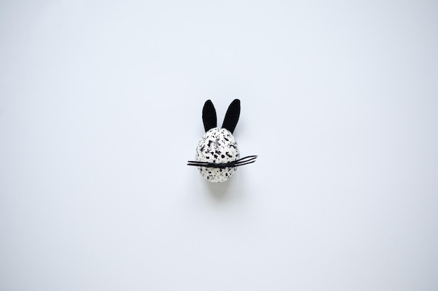 Easter egg decorated as spotted black and white bunny on the white background