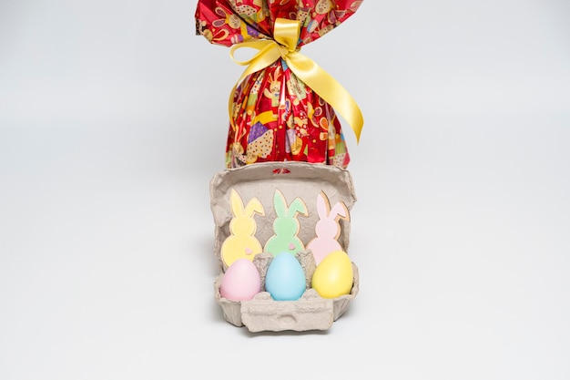 Easter egg in lovely red packaging with yellow ribbon and several small colorful eggs with ornament bunnies Isolated on white background Closeup Copy space