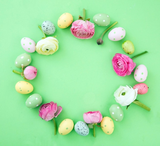 Easter egg and Spring flowers decoration wreath on green pastel background