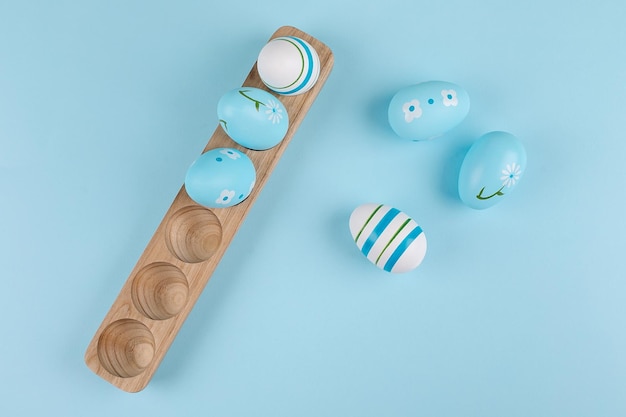 Easter egg on wooden tray on blue background Flat lay top view