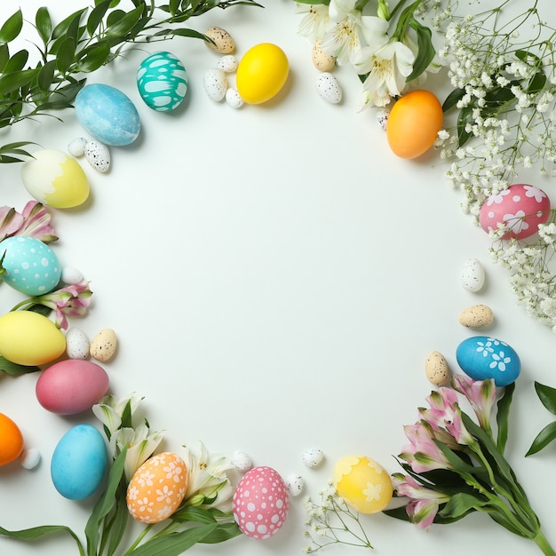 Easter eggs and beautiful flowers on white background, space for text