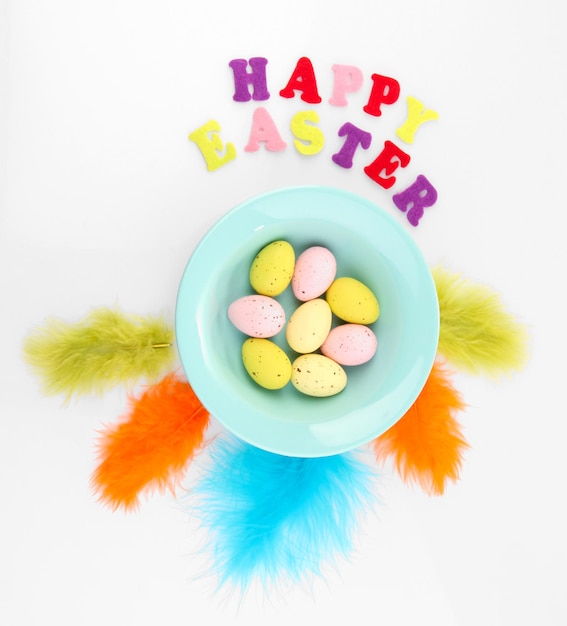 Easter eggs in bowl and decorative feathers isolated on white