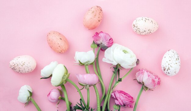 Easter eggs and Buttercups flower bouquet on pastel pink background