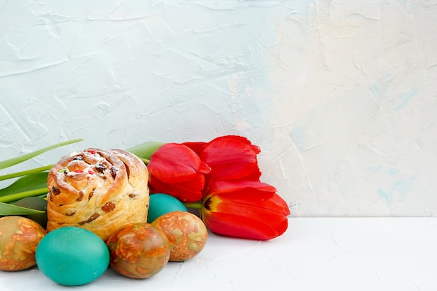 Easter eggs and cake with tulips on blue background