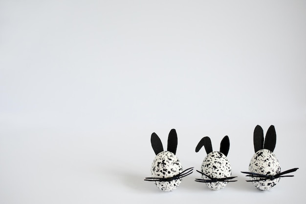 Easter eggs decorated as spotted black and white bunnies on the white background copy space