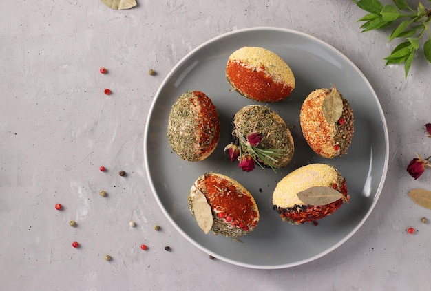 Easter eggs decorated with different spices and cereals without dyes and preservatives on a plate on a gray concrete background Top view