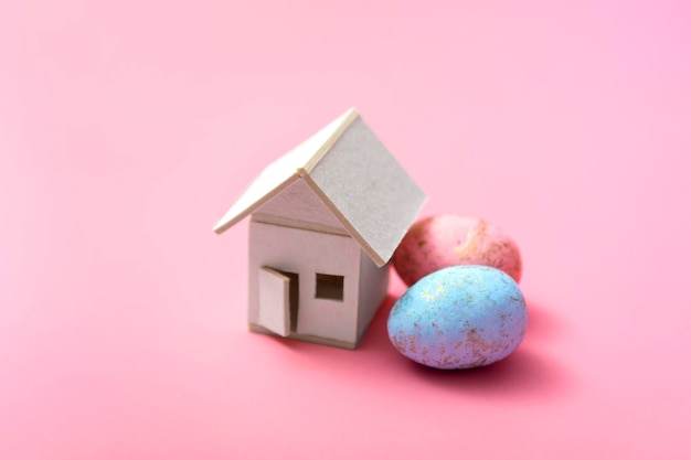 Easter eggs and house on a pink background. Family holiday concept. Greeting card template. With copy space. close up