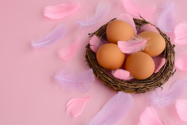 Easter eggs in a nest, pink purple feathers on a pastel pink background. Easter background, copy space