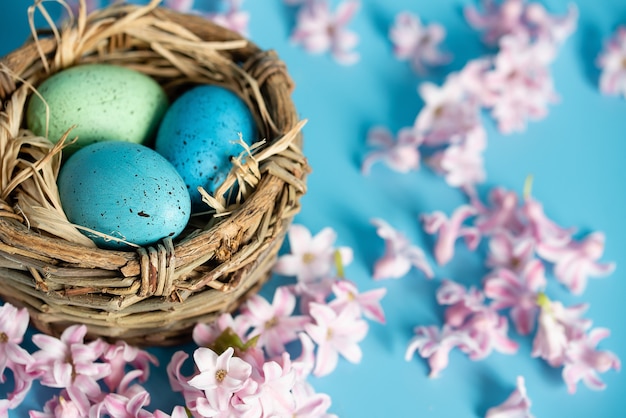 Easter eggs in nest of spring flowers. Top view with copy space.